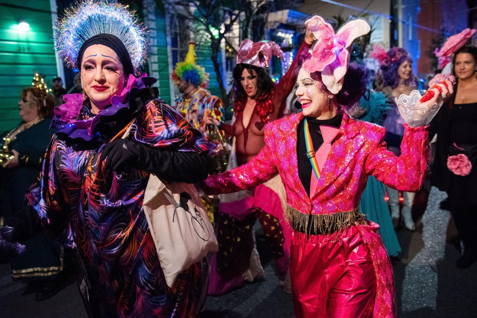 Costumed parade participants in purple and pink on a French Quarter street