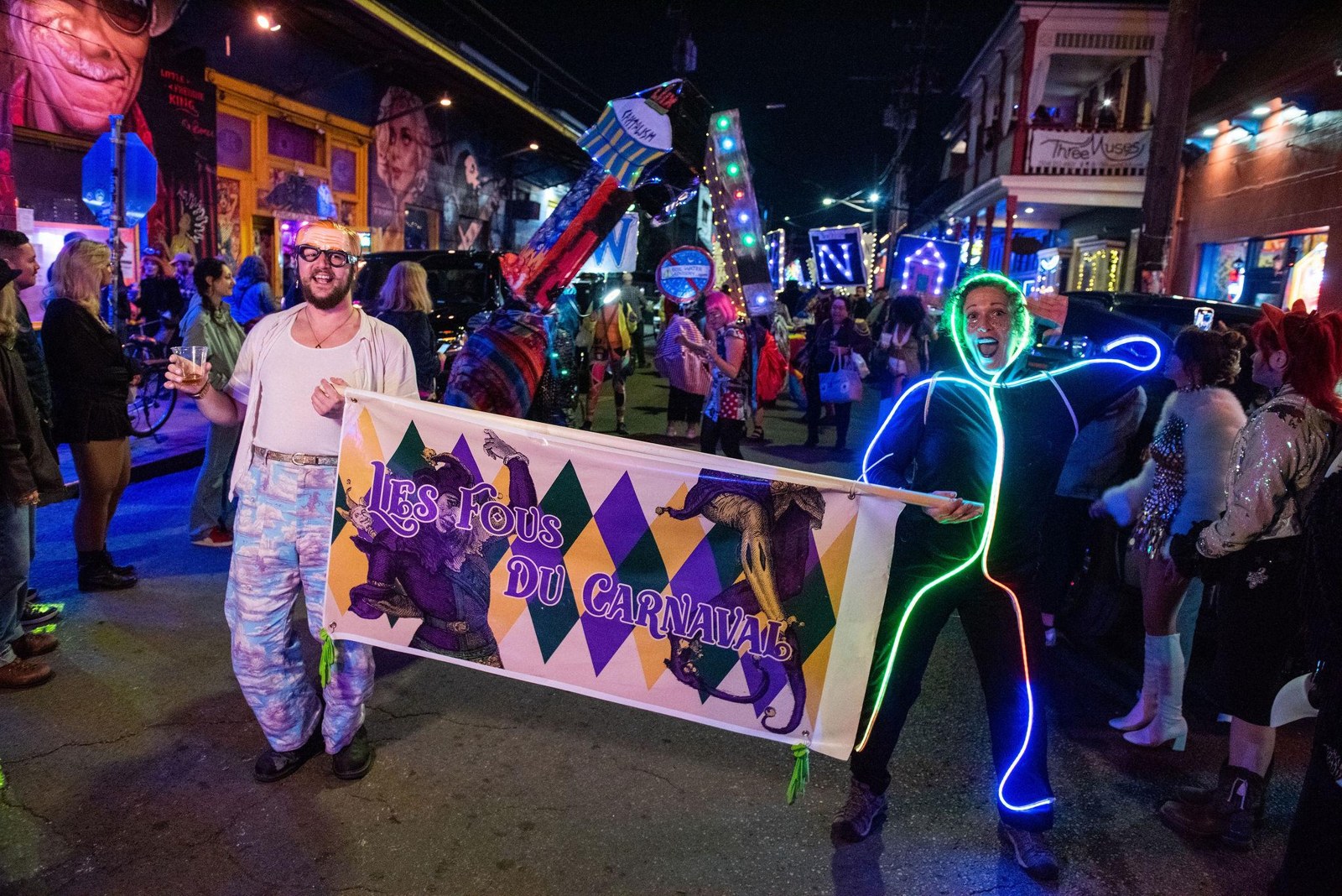 Les Fous du Carnaval banner carried along a nighttime parade route