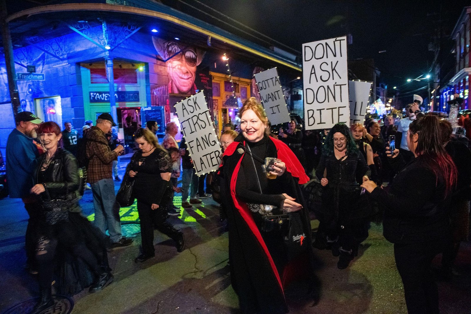 Parade participants in dark costumes carrying handmade signs