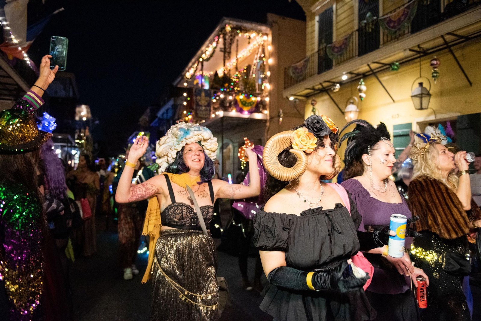 Revelers waving to spectators under a French Quarter balcony