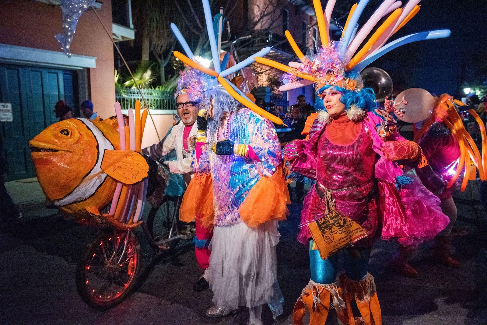 Participants carrying brightly colored sculptural costumes